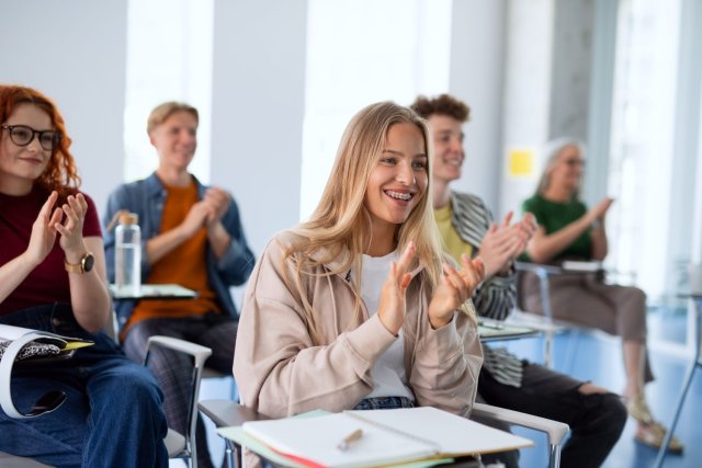 Excited international students in a classroom, actively studying English and enjoying their learning experience together