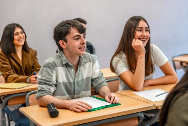 A diverse group of international students happily participating in an English course, showcasing enthusiasm for learning
