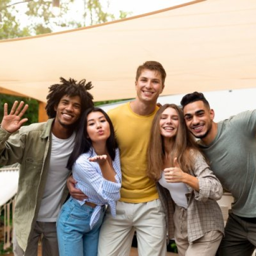 Adult international students laughing with their English teacher over a tongue-twister challenge in a bright classroom
