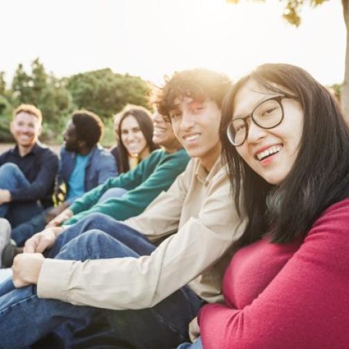 VI Academy students enjoying Malaysian street food at a busy night market, laughing and holding skewers and drinks